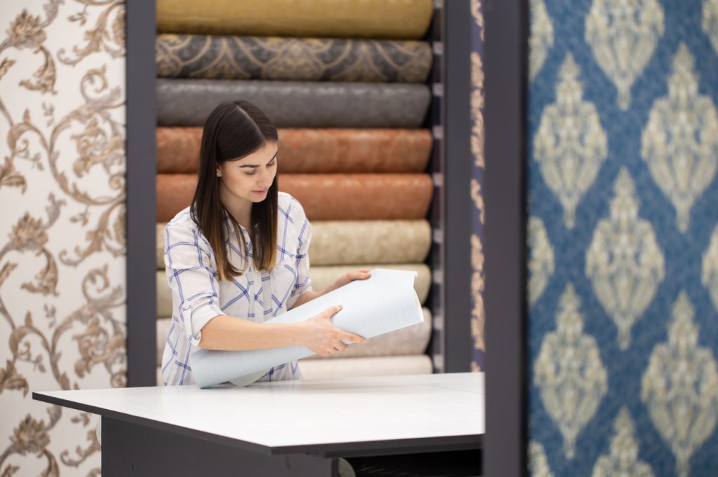 Woman examining wallpaper samples at a display counter